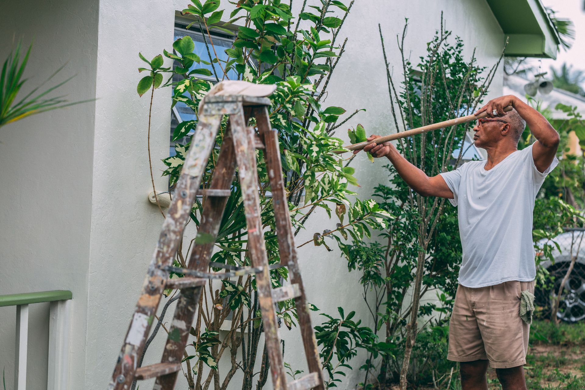 A painter rolling fresh paint onto a home exterior