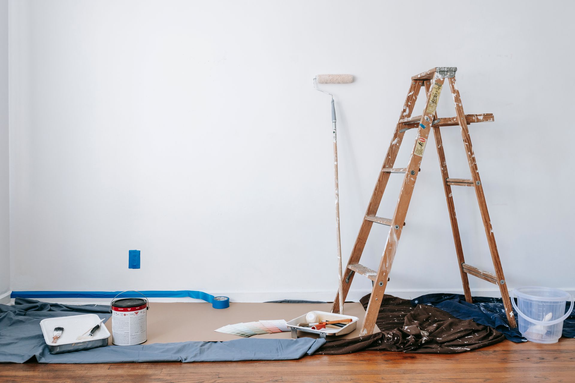 Drop cloths, taped trim, and a ladder — prep before painting